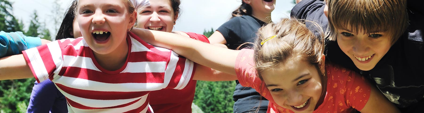 Eine Gruppe Kinder speilt und freut sich draußen auf einer Wiese
